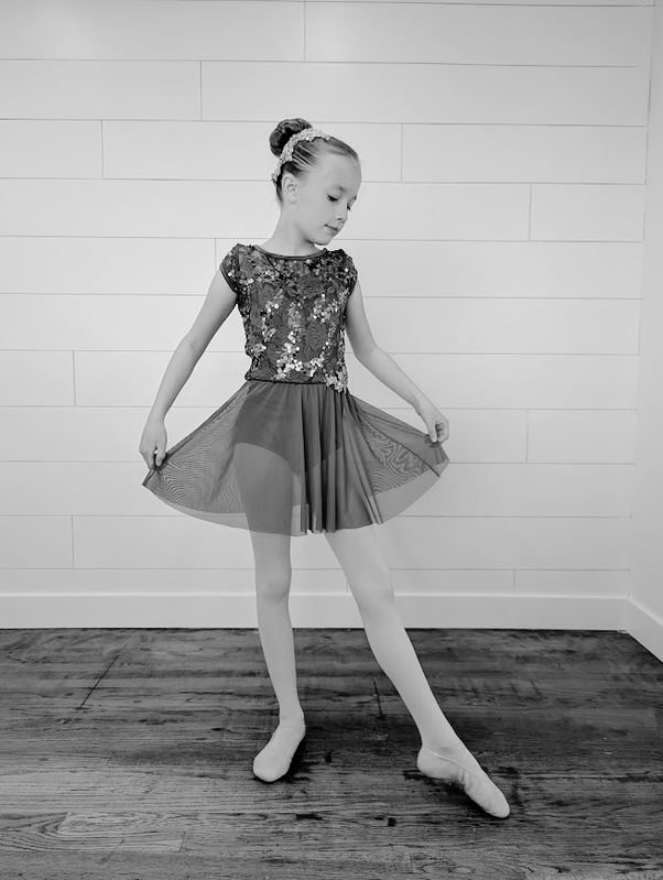 A dancer in a graceful pose holding her skirt